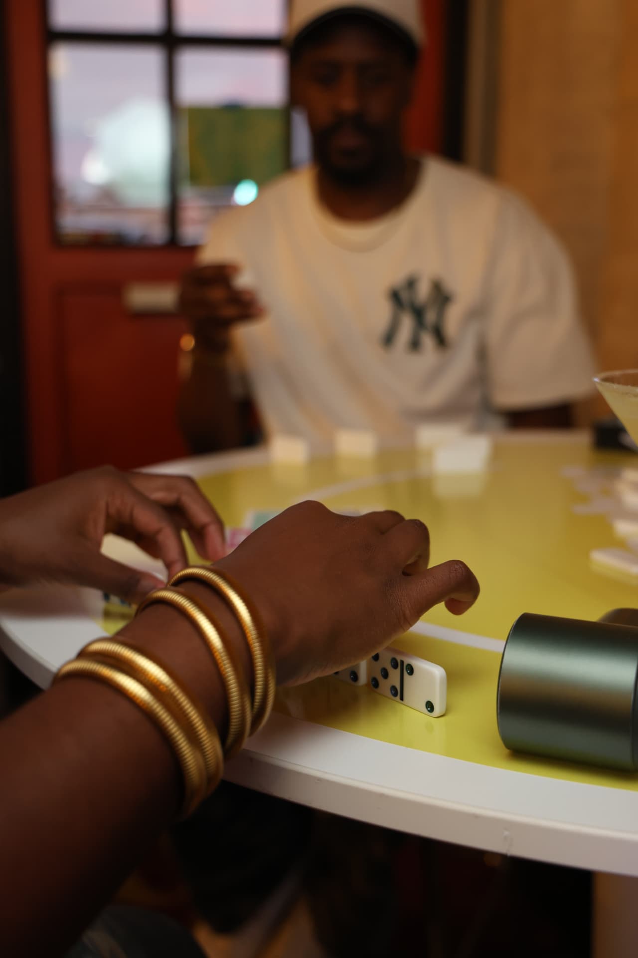 Players laying dominoes on a bright yellow table