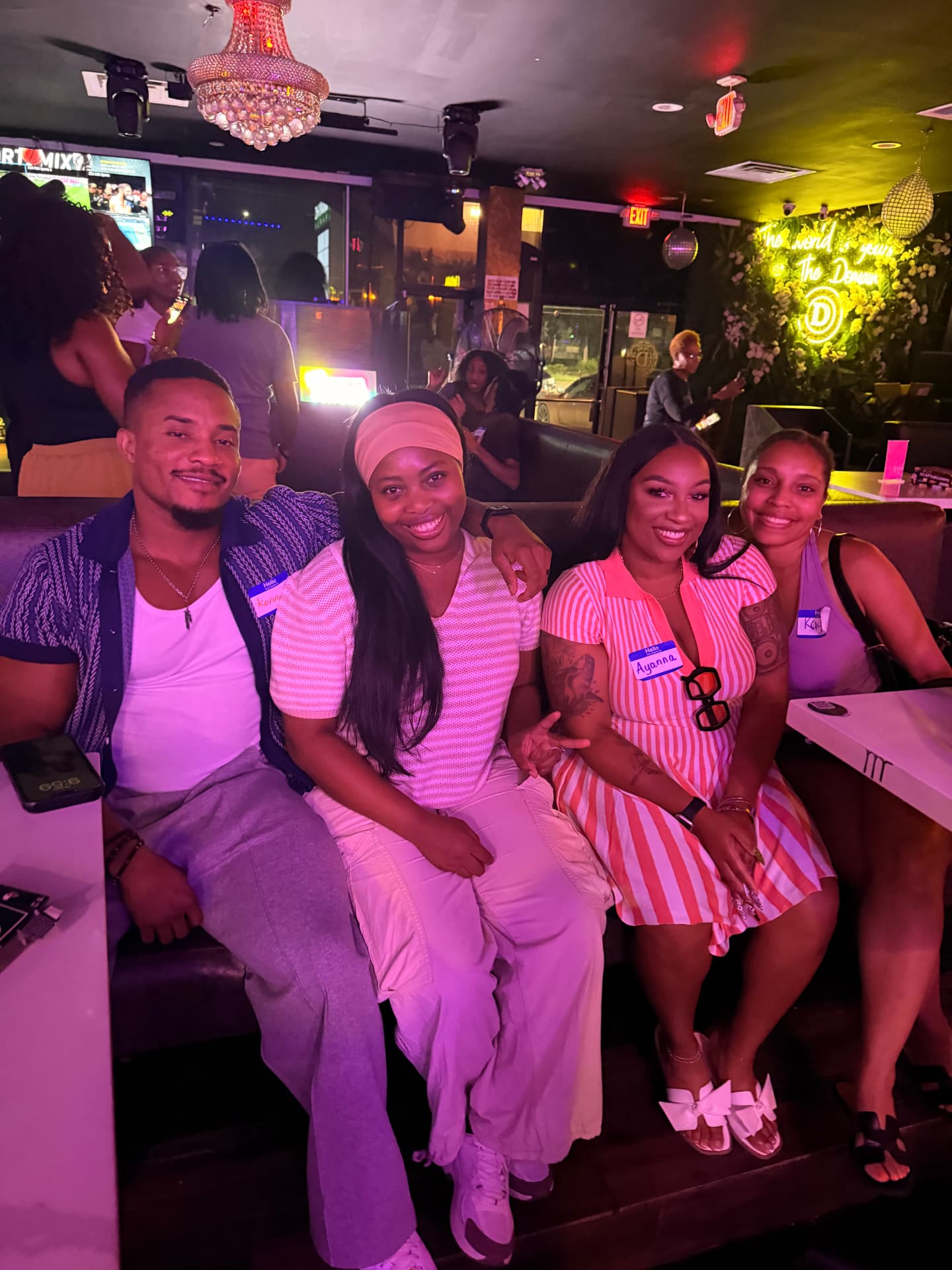 Four guests seated together in a pink-lit lounge