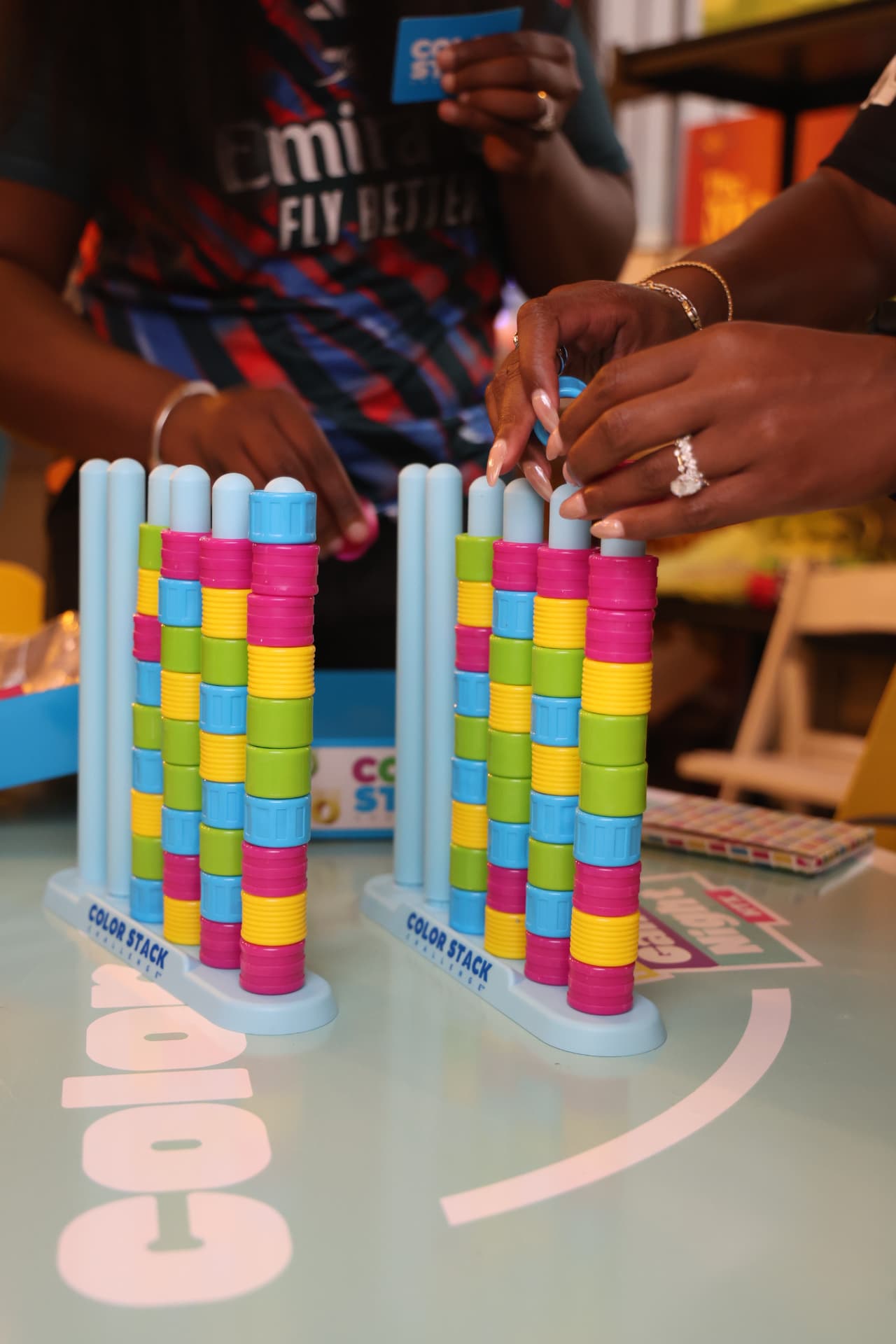 Hands reaching for colorful stacking game pieces