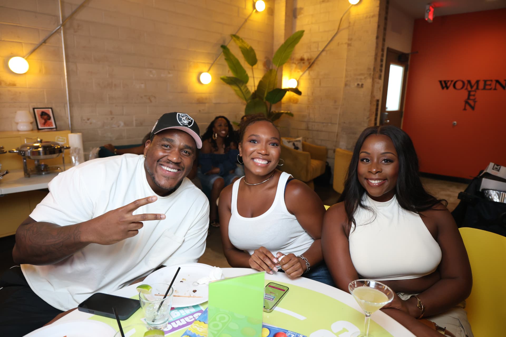 Three smiling guests at a brightly lit game table
