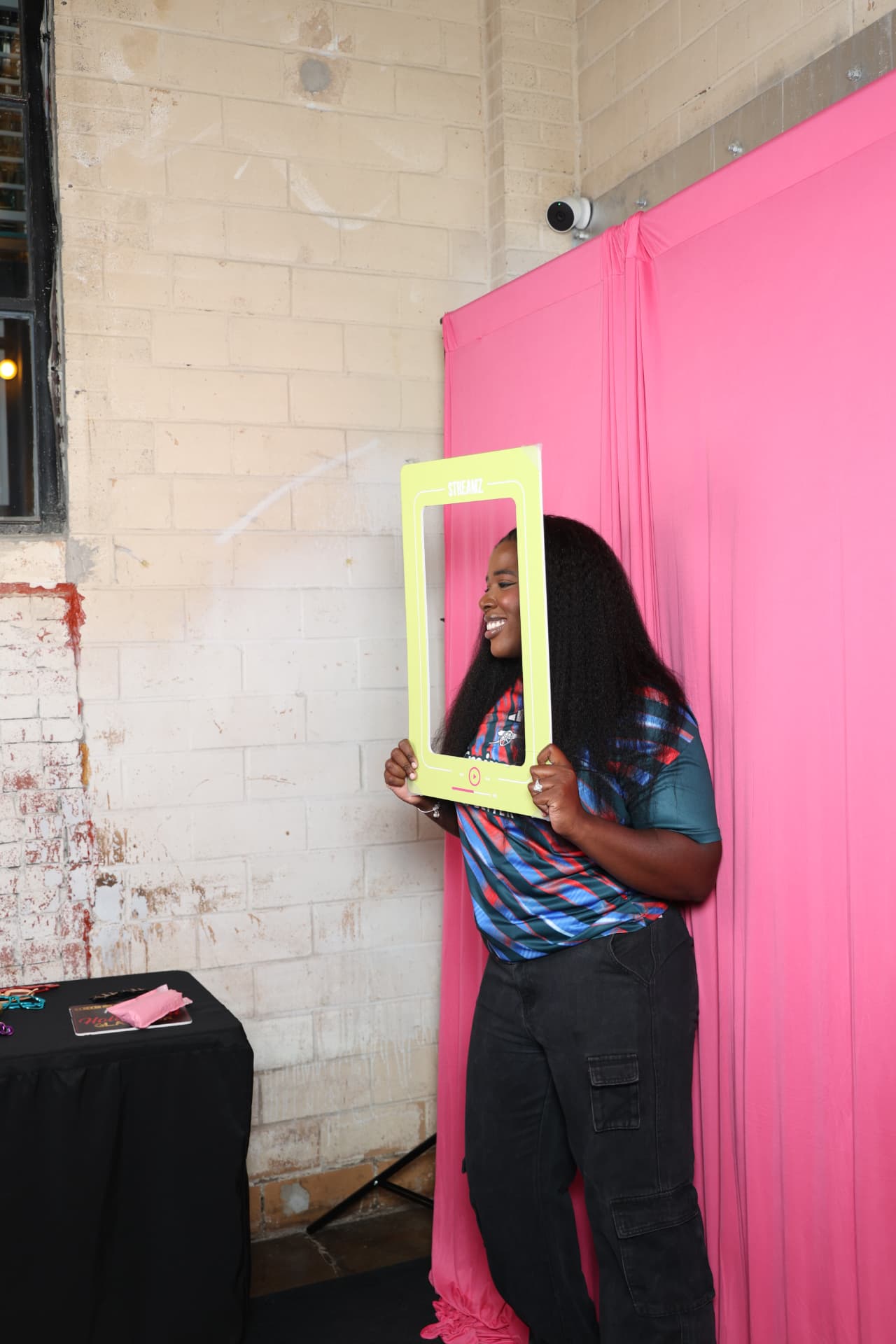 Guest holding a lime photo frame in front of a pink backdrop