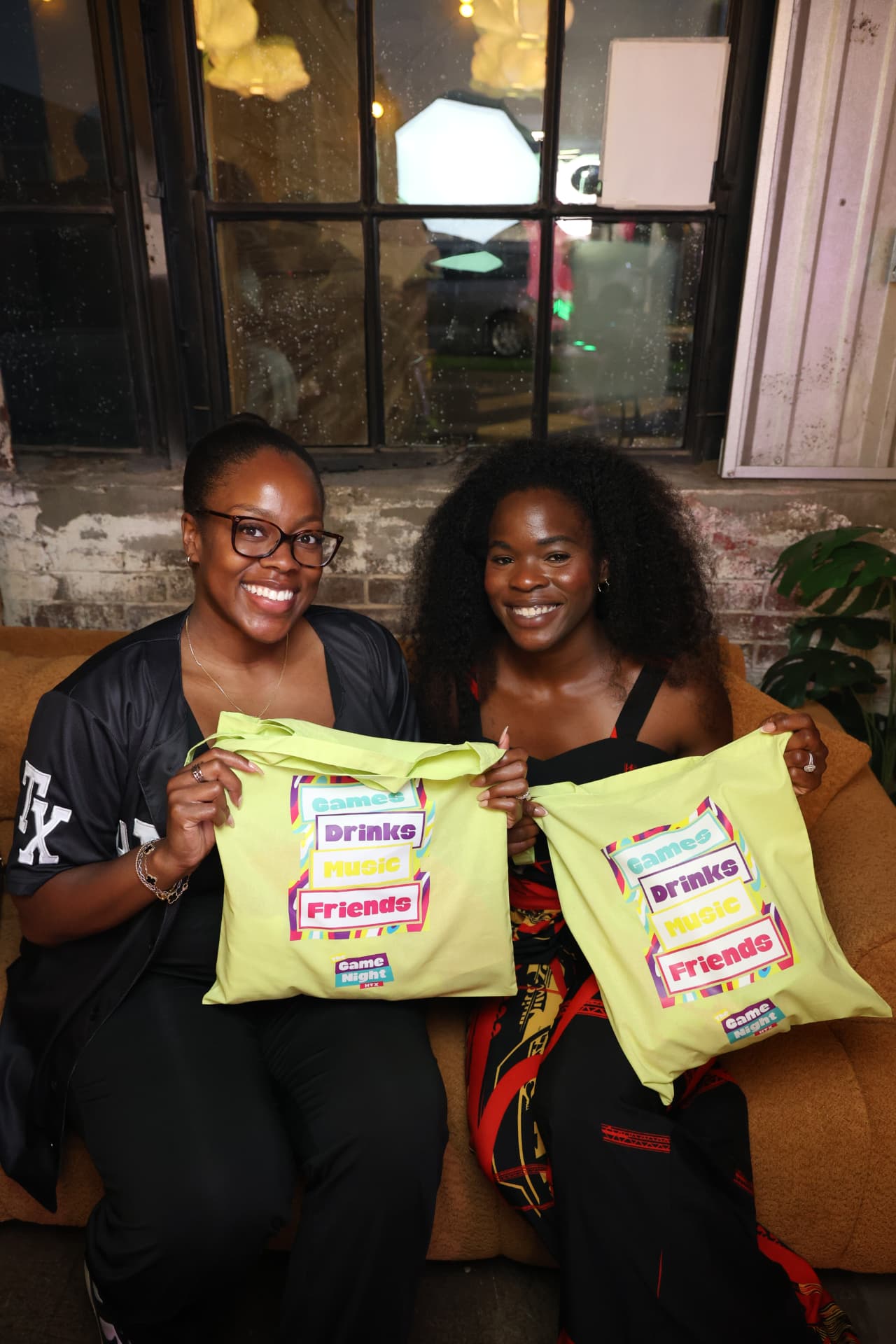 Two guests holding Game Night HTX tote bags